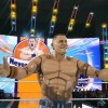 Elite Mattel John Cena doing his entrance, standing in front of his titantron with his arms spread out.