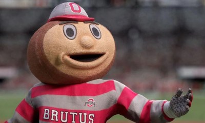 Ohio State's Brutus Buckeye Mascot standing with his hand extended out.